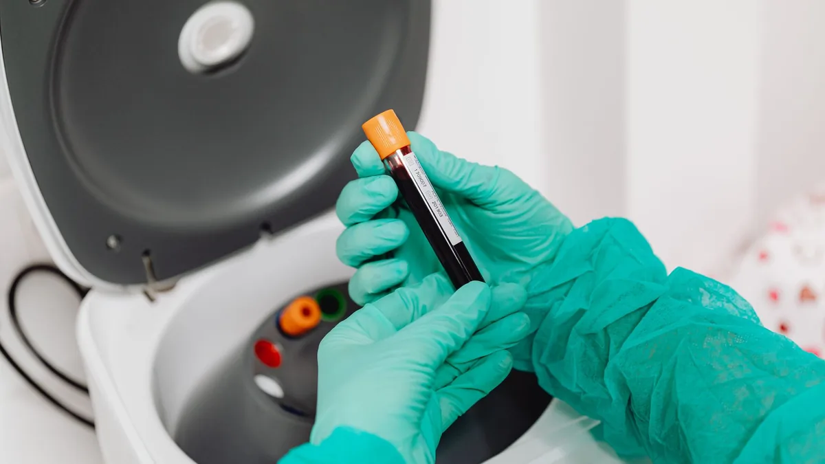 Laboratory scene with a healthcare professional preparing a blood sample for analysis using a centrifuge.