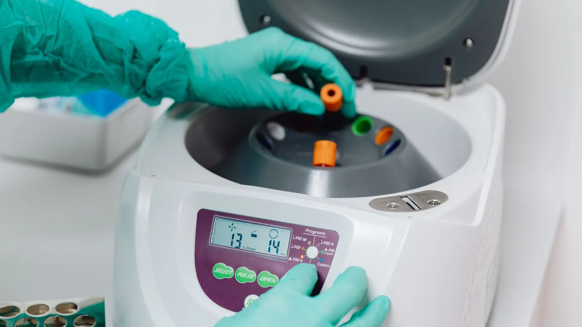 A close-up of a lab technician using a centrifuge to process blood samples in a medical laboratory.