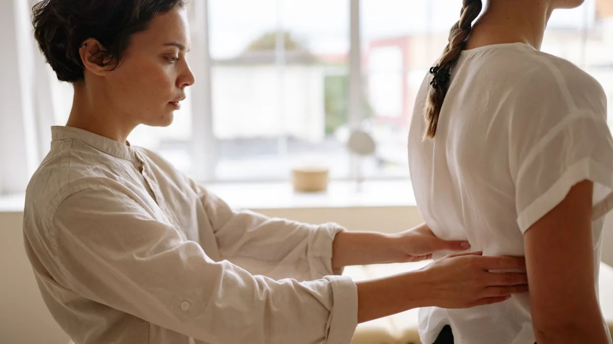 A physiotherapist performs a back alignment therapy on a patient indoors.