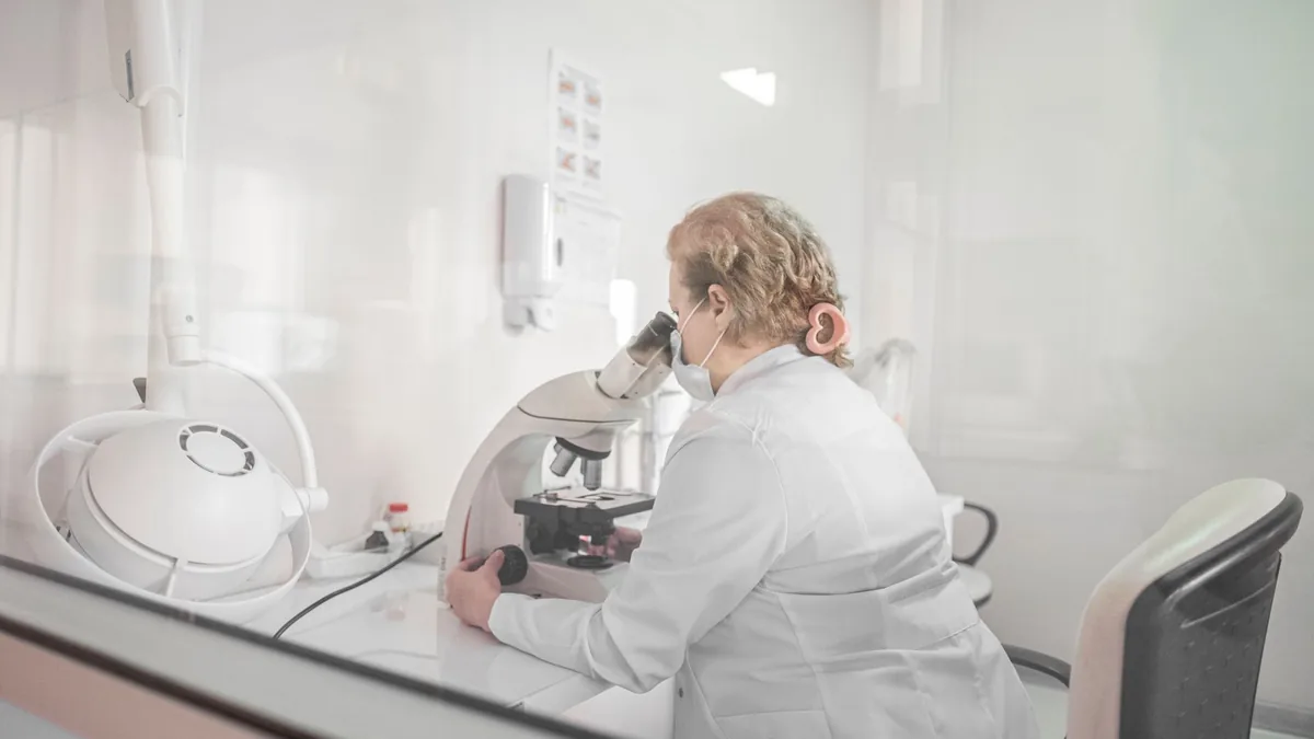 A scientist works with a microscope in a bright, modern lab setting, wearing a lab coat.