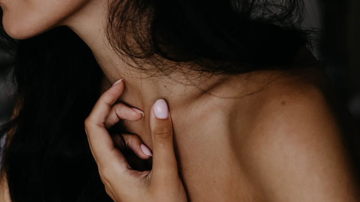 Artistic close-up photo of a woman's neck and hand with a focus on skin texture and nails.