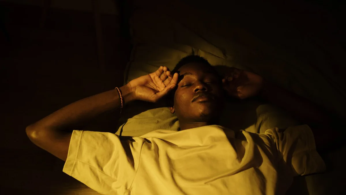 A man lying down in a cozy, warm-lit room, peacefully asleep during the night.