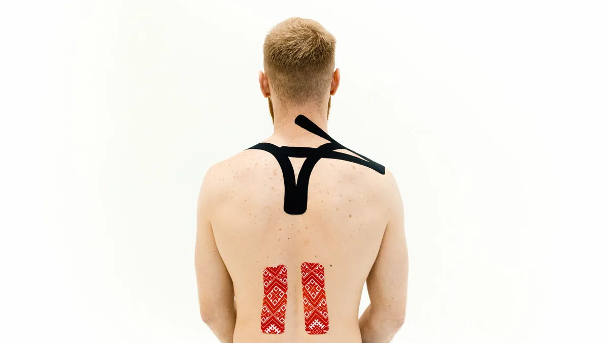 Man with kinesio tape on his back for muscle support and pain relief.