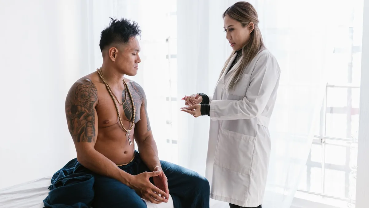 A doctor consults with a shirtless man in a clinical setting.