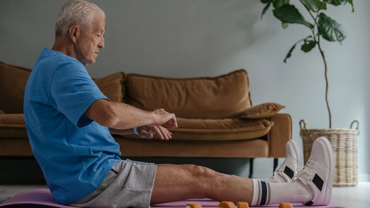 Older man doing floor exercises on a mat at home as part of back pain care without surgery