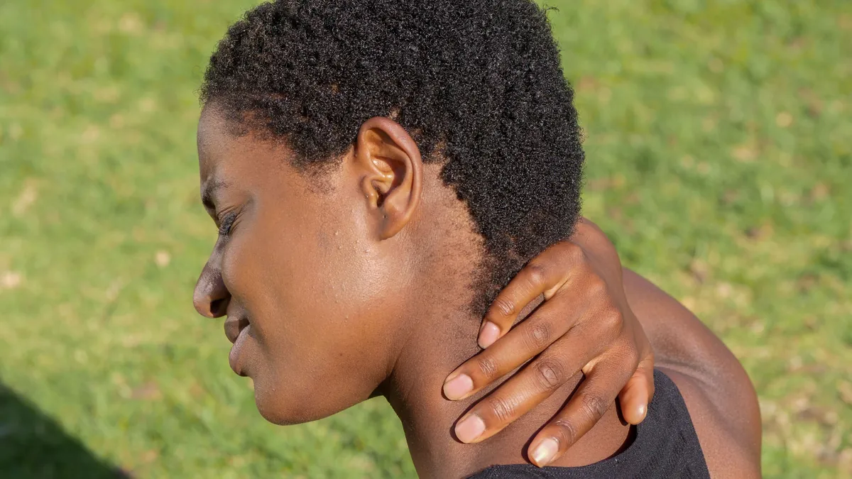 Woman pressing the back of her neck where cervical facet joint pain is felt