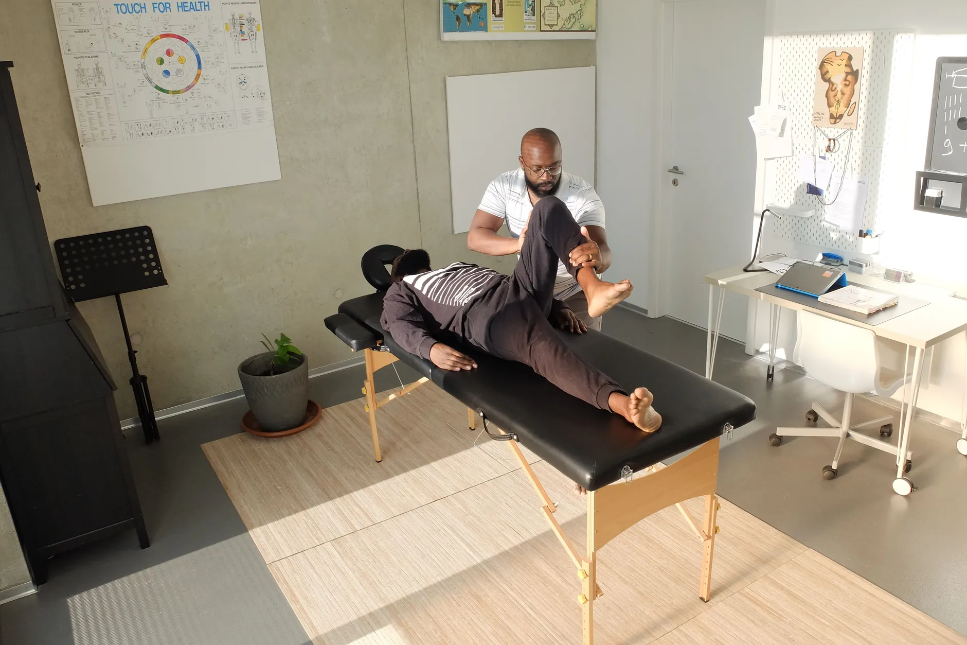 Therapist guiding a patient through a leg exercise on a treatment table in a rehabilitation room