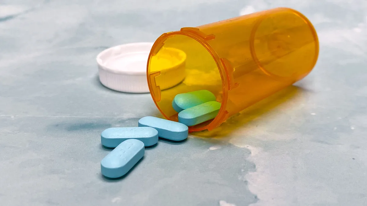 Prescription pill bottle tipped over with tablets spilling onto a table