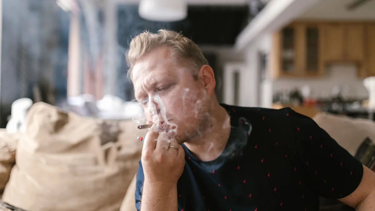 Man smoking a cigarette while sitting on a couch at home