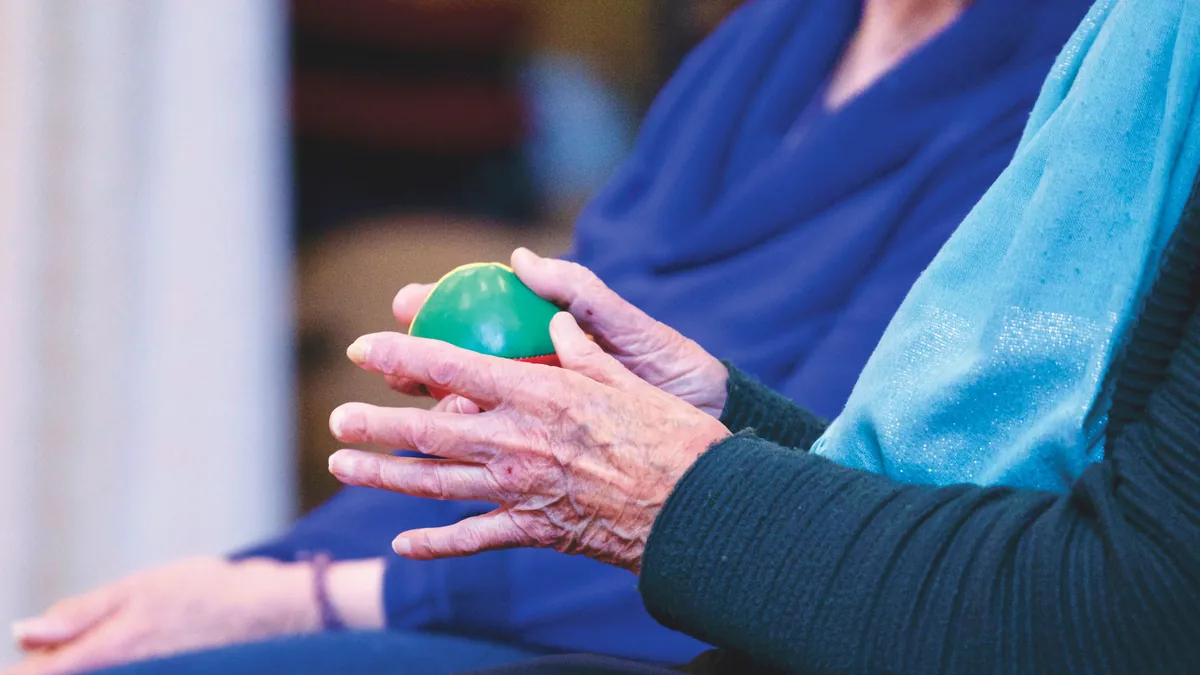Older woman squeezing a soft therapy ball to work the joints of her hand